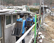 Volunteers transport briquettes in relay along narrow alleys